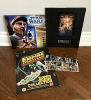 Three Star Wars themed items: animated Clone Wars calendar, Phantom Menace hardcover booklet, Empire Strikes Back sticker booklet.