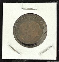 Obverse side showing conjoined profiles of King George V and Queen Victoria with inscription '1867 CONFEDERATION 1927'. Medal held in white cardboard holder with plastic covering.