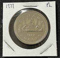 Front side of 1977 Canadian 1 dollar coin showing the year, denomination, and canoe design.