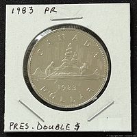 Front side of the 1983 Canadian proof dollar coin in protective holder, showing the canoe design with voyageurs and inscriptions.