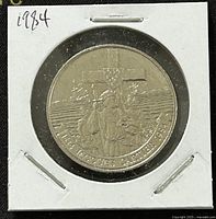 Reverse side of 1984 Canadian 1 dollar coin depicting Jacques Cartier landing scene and commemorative inscriptions.