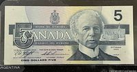 Front view of the 1986 Canadian 5 dollar banknote showing Sir Wilfrid Laurier's portrait, denomination, and Bank of Canada markings.