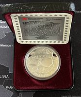 Closed view showing the silver coin in a burgundy velvet display case along with the Royal Canadian Mint certificate.