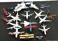 Top-down view showing the collection of 20 die cast airplanes, jets, and helicopters arranged on a black surface.