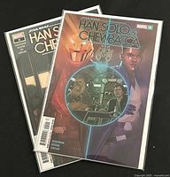 Two Marvel Star Wars comic books stacked showing key cover artwork of characters including Han Solo and Chewbacca.