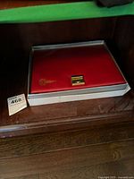 Closed red leatherette presentation case with gold Olympic emblem on lid