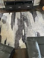 Overhead view of rug showing abstract pattern in beige, cream, brown, black and gray with indicate signs of use