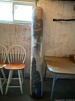 Overall view of the rolled-up area rug in its original plastic packaging, showing the size and sealed condition.