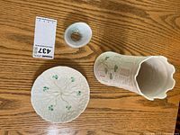 Top-down photo showing the Belleek vase, plate, and a Kosta Boda cup on a wooden table.
