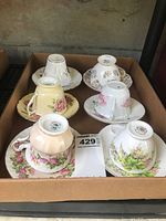 Top-down view of six fine bone china cups upside down on matching saucers showcasing various floral patterns and colors including pink, yellow, purple, and multicolor blooms.