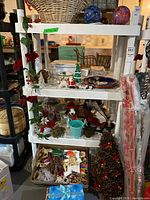 Front angle view showing 4-tier white plastic shelving unit with various decorative items on shelves, not included in sale.