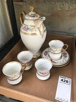 Photo showing entire tea/coffee pot with four cups, some saucers visible, set inside a cardboard box