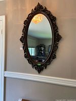 Full view of the oval wall mirror hanging on a beige wall, showcasing its overall size and shape.