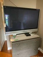 Panasonic 50-inch plasma TV on silver stand with black screen, placed on a cabinet.