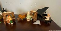 Four miniature piano music boxes displayed together showing different piano styles and figurines