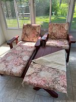 Photo showing chaise lounge, armchair and coffee table set placed inside sunroom near windows, floral cushions on lounge and chair, wood armrests visible.