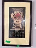 Frontal view of the framed Salvador Dalí calendar print measuring 40x8 inches, showing the surrealist face artwork and calendar below.