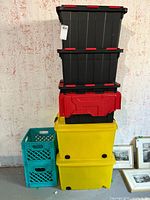 Stacked set of storage containers and crates in various colors including yellow, red, black, and turquoise creating a clear view of the lot contents.