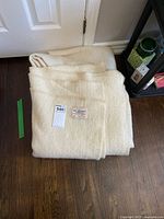 Two folded cream wool blankets stacked on the floor near a door.