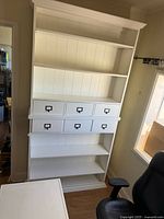 Two white wood bookcases stacked, showing beadboard back, crown molding and shelves with six small drawers each.