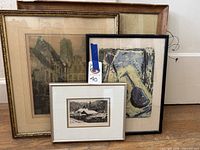 Four framed art pieces grouped together showing wear on frames and varied styles including detailed etching and abstract print
