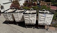Four canvas laundry carts side by side outdoors