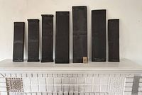 Seven wood carved dark wood panels standing upright on a mantel, showing front sides with carved Japanese script.