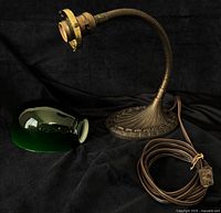 Lamp base with gooseneck arm and separate green glass shade, brown power cord visible