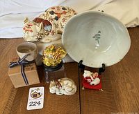 Overview photo showing all six items grouped together: large porcelain Maneki Neko, hand-painted bowl, miniature cup and box, sleeping cat figure, gold-tone elephant, and miniature Maneki Neko on red cushion.