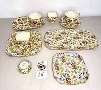 Full lot image showing 11 assorted Royal Winton dishes in floral and fruit chintz patterns lying on a white surface.