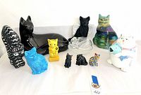 All 11 cat figurines arranged in a row showing various styles, colors, and sizes