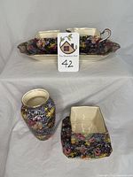 Photo showing the floral patterned tray, sugar and creamer set on tray, bud vase and square plate arranged on a table.