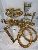 Full collection arranged showing gold tray, decorative swan vase, figures, frames, and tableware items