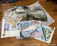 Group of multiple art posters spread out on floor showing variety of artworks and styles.