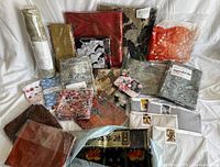 Overview image showing an assortment of fabric panels and rolls in various colors including reds, browns, and muted greens with some still in original plastic packaging or wrapping.