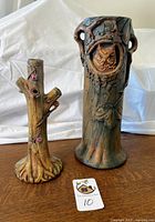 Overall view of both Weller tree trunk vases on wood surface.