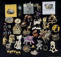 Full view of 31 animal-themed brooches arranged on black fabric, showing varying styles and colorful designs.