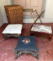 Full view of all five lot items arranged together showing the two cast iron footstools, the wooden footstool, wicker hamper, and knitting bag holder.