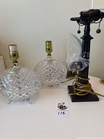 Full view of the three lamps showing two cut crystal lamps and one black metal lamp base.