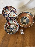 All four pieces shown together on table, two bowls and two scalloped plates, exhibiting traditional Imari colors and designs
