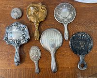 Six hand mirrors laid out around a small round compact