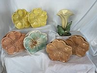 Overview of six flower wall pockets on display alongside calla lily vase