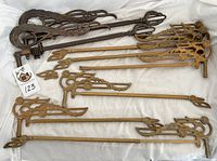 Collection of vintage metal and cast iron curtain rods with ornate finials and swivel joints, shown laid on white cloth.
