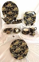 Full set arranged showing various pieces of Royal Winton Pekin pattern dishes and serving pieces with black background and colorful scenic design.