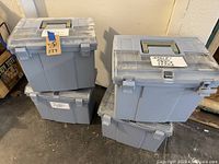 Four blue plastic file storage bins stacked, showing translucent latching lids and built-in handles, with labels on lids indicating document categories.