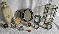 Overall view showing stoneware hot water bottle at left, brass glass display case at right, and assorted frames and brooch centered