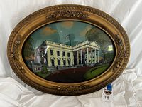 Full view of an oval framed vintage reverse glass painting showing the White House.