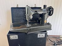 Black Singer sewing machine mounted on its base, set atop the open black carrying case
