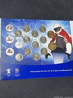 Front view of the folder showing Canadian Olympic quarters arranged on a winter sports themed background, featuring a snowboarder image and blue background with logos.