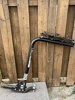 View of full 4-bike rack with trailer ball hitch mount against wooden fence.